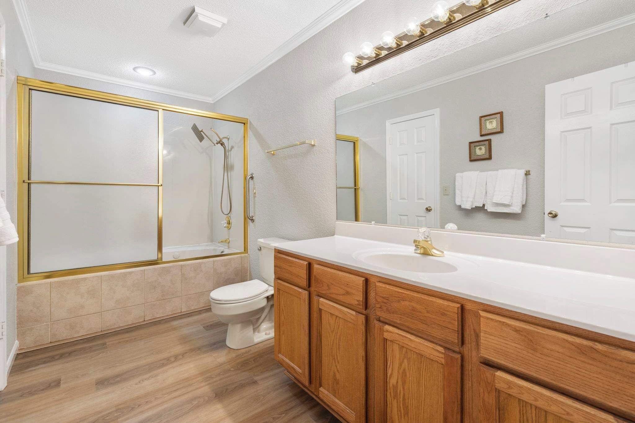 A modern bathroom with a large mirror, a walk-in shower, and wooden cabinets.