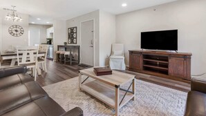 A modern living room with a sofa, coffee table, TV, and dining area. - Hillside Duo - 2 Units in The Vineyards Resort (Branson)