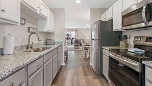A modern kitchen with granite countertops, stainless steel appliances, and light-colored cabinetry. - Hillside Duo - 2 Units in The Vineyards Resort (Branson)