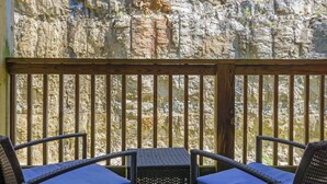 Eine Holzterrasse mit Korbstühlen und einem Tisch, mit Blick auf eine steile Felsküste.