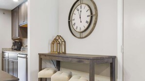 Eine Küche mit Holzschränken, einer Kaffeemaschine und einer Wanduhr.