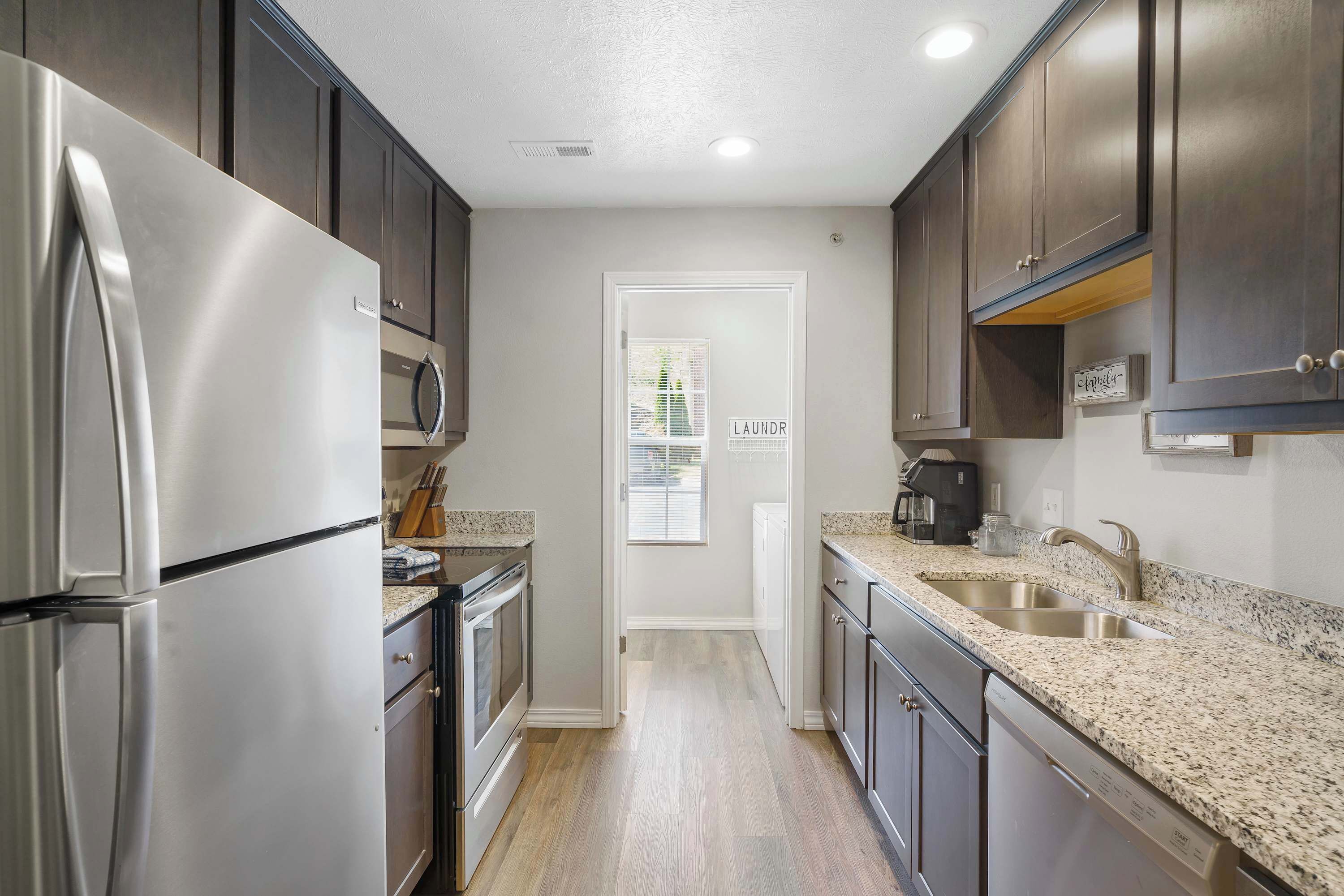 A modern kitchen with stainless steel appliances, granite countertops, and dark cabinetry.