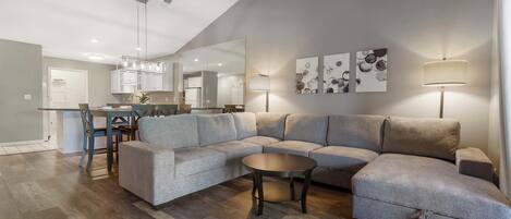 A modern living room with a sectional sofa, a round coffee table, and a dining area with a chair and table.