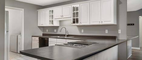 Una cocina moderna con armarios blancos, encimera negra y pileta de acero inoxidable.