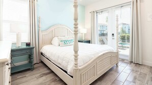 A four-poster bed with a white headboard, a bedside table with a lamp, and a window with curtains. - Shake Shack Heated Pool & Hot Tub (Kissimmee)