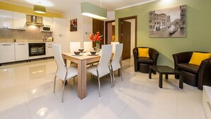 Un salon moderne comprenant un coin repas, une cuisine et un tableau représentant un paysage urbain.