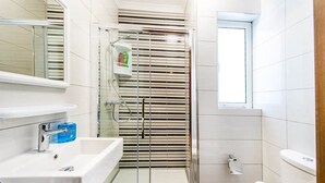 Une salle de bain moderne avec une douche à parois de verre, un lavabo blanc et des toilettes.