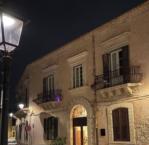 A historic building with ornate balconies, arched doorways, and a street lamp.