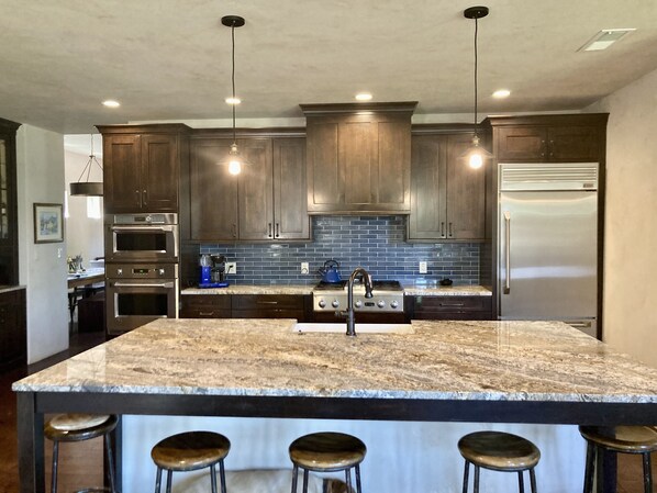 Enjoy cooking in this well-equipped kitchen with a large island, refrigerator, oven, and microwave.