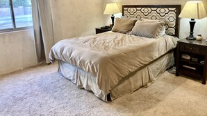 A bedroom with a bed, two bedside tables with lamps, a patterned headboard, and a window with curtains. - Custom built family home, close to balloon fiesta park  (Albuquerque)