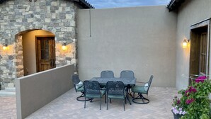 A patio with a stone wall, a wooden door, and a table with chairs. - Custom built family home, close to balloon fiesta park  (Albuquerque)