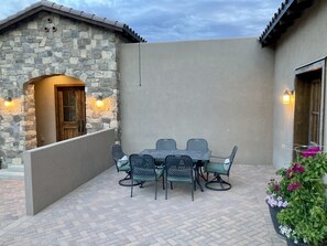 A patio with a stone wall, a wooden door, and a table with chairs. - Custom built family home, close to balloon fiesta park  (Albuquerque)