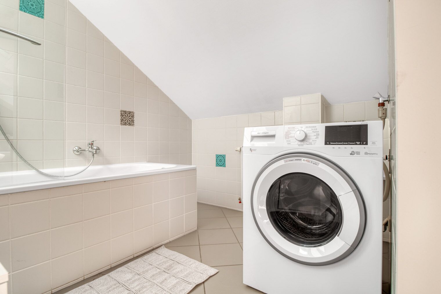 A laundry room with a washing machine and a bathtub.