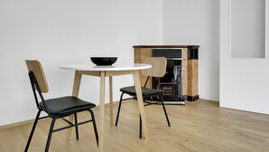 Een minimalistische eethoek met een ronde tafel, twee stoelen en een zwarte kom.