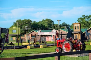 A red tractor at a start line, a sheriff's office, and a green building with a checkered flag. - Waterfront Luxury RV Lot w/ Private Dock & Grill 430 (River Ranch)