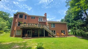 A two-story brick house with a balcony, a covered porch, and a staircase leading to the upper level.