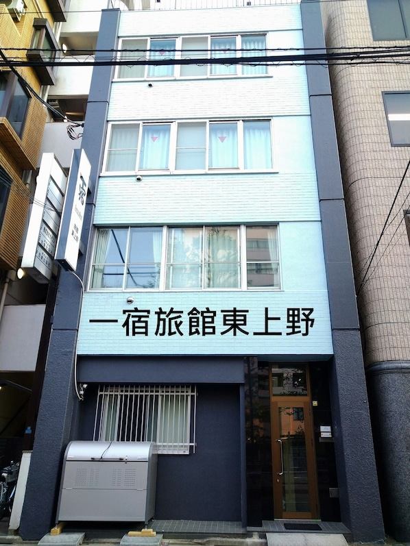 Ein Gebäude mit einem Schild, auf dem „一宿旅館東上野“ steht.
