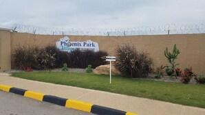 A sign for Phoenix Park Village with a barbed wire fence in the background.