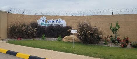 A sign for Phoenix Park Village with a barbed wire fence in the background.