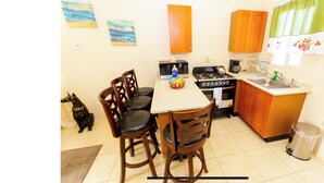 A compact kitchen with a dining table, chairs, a stove, microwave, and cabinets.