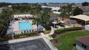 Un quartier résidentiel doté d’une piscine, de chaises longues et d’un patio couvert.