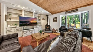 Een gezellige woonkamer met een open haard, leren banken, een salontafel en een grote televisie.