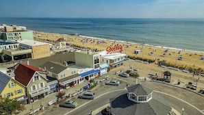 Uma cidade costeira com uma praia, um edifício 'Dolley' imponente e uma mistura de edifícios comerciais e residenciais.