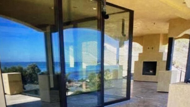 Un saló modern amb una porta de vidre que dona a un balcó amb vista al mar.