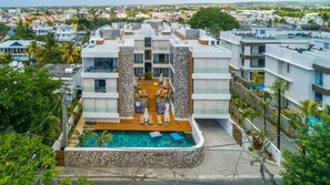 A modern hotel with a rooftop pool, multiple balconies, and a view of the surrounding cityscape. - Immaculate 2-Bed Apartment in Pereybere Grand Baie (Grand Baie)