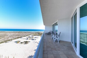 Enjoy the ocean view from this balcony with a table and chairs.