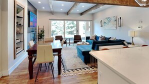 Amplia sala de estar con mesa de comedor, sofá y un ventanal que ofrece vistas al exterior.