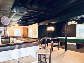 Relax and socialize in this vibrant space, featuring a pool table, foosball table, and bar counter with stools.