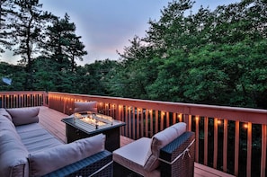 Eine Terrassenausstattung mit Sofa, Stühlen und einem Tisch mit Beleuchtung.