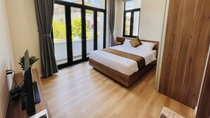 A modern hotel room with a large bed, a desk with a computer, and a view of the outside.
