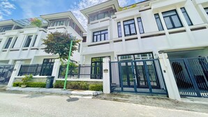 A modern residential building with a symmetrical facade, large windows, and a gated entrance.