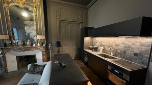 Ett modernt kök med en central köksö, en inbyggd ugn och en kakelbeklädd vägg bakom arbetsbänken.