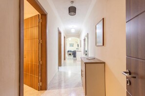 A hallway with a wooden door, a desk, and a mirror on the wall.