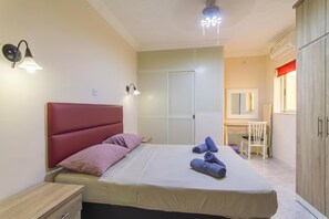 A bedroom with a bed, bedside table, wall-mounted lamp, wardrobe, and a desk with a chair. - Sunny pool and terrace - Merill nb3, Mellieha, Malta (Mellieha)