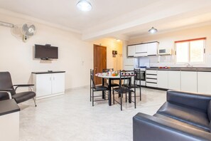 Une cuisine moderne avec des meubles blancs, un four à micro-ondes et un coin repas comprenant une table et des chaises.