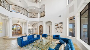 A spacious living area with a high ceiling, a grand staircase, and a large window offering a view of the outdoors. - Legends Palmer: Private Pool, Game Room, Theater, Gym, Free Water Park, Near Disney (Kissimmee)
