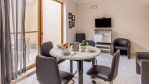 A dining area with a round table, chairs, a television, and a sliding glass door. - Sunny pool and terrace - Merill nb1, Mellieha, Malta (Mellieha)