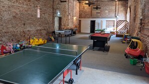 Ett rymligt inomhusområde för rekreation och lek, med ett bordtennisbord, ett fotbollsspel och diverse leksaker för barn.