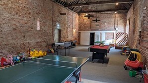 Un'ampia area interna con tavolo da ping pong, tavolo da biliardo e diversi giochi per bambini.