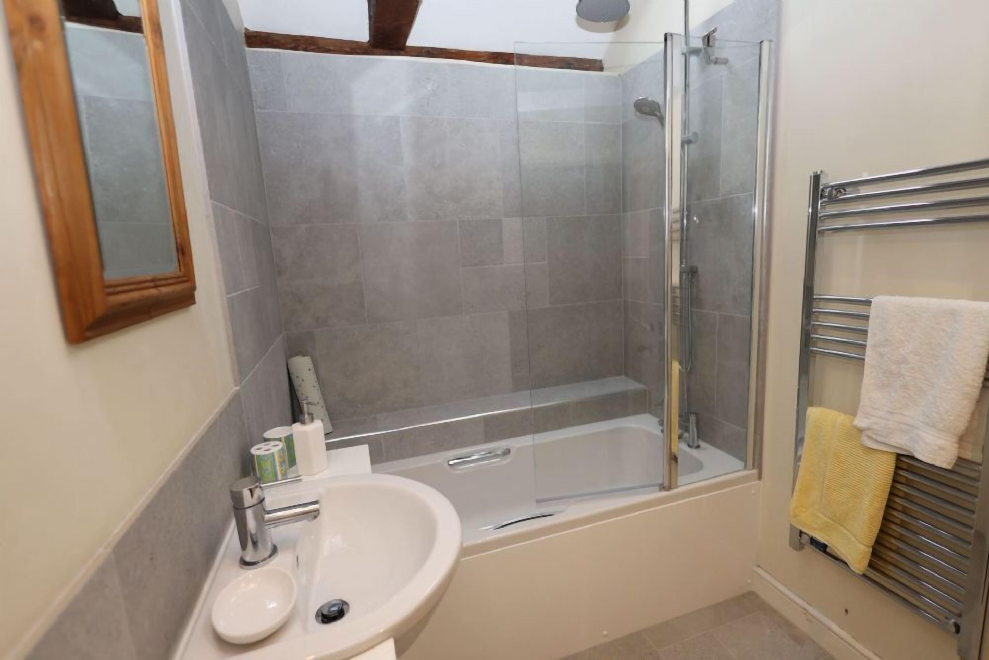 A bathroom with a bathtub, a glass-enclosed shower, and a sink.