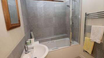 A bathroom with a bathtub, a glass-enclosed shower, and a sink.