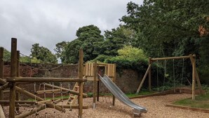 Un'area giochi con strutture in legno, tra cui uno scivolo e una rete da arrampicata.