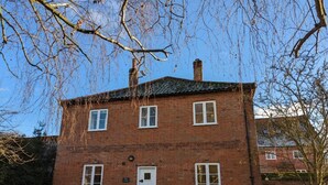 Un edificio a due piani in mattoni con una porta bianca e diverse finestre.