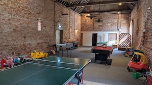 Amplio espacio interior con mesa de ping pong, mesa de billar y varios juguetes infantiles.
