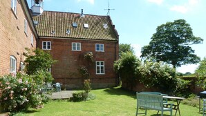 A brick house with a tiled roof, a lawn, and a bench. - Stables cottage - fully accessible with you in mind (Norwich)
