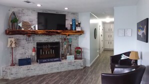 Ein Wohnzimmer mit Kamin, Flachbildfernseher und einem hölzernen Kaminvorsatz.